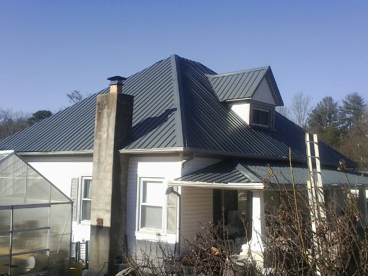 Dark blue standing seam metal roof on a white farmhouse with dormer — Slate & Tile Roof Repair by Roofing Brothers in San Dimas