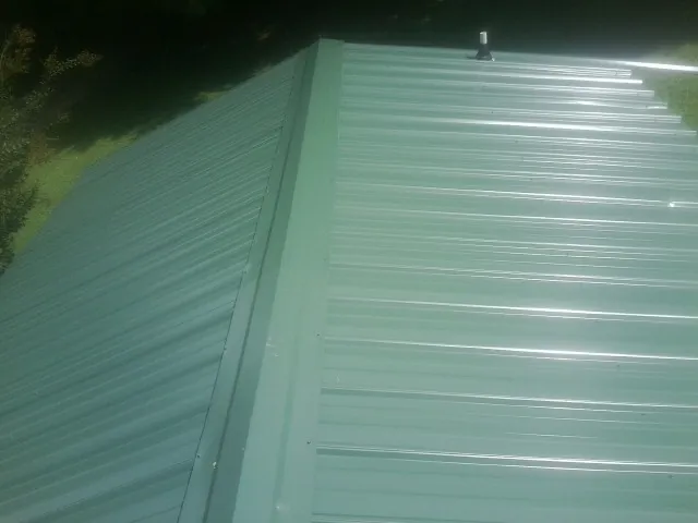 New green metal panels meeting at the ridge of a roof — Flat Roof Repair work by our crew in San Dimas