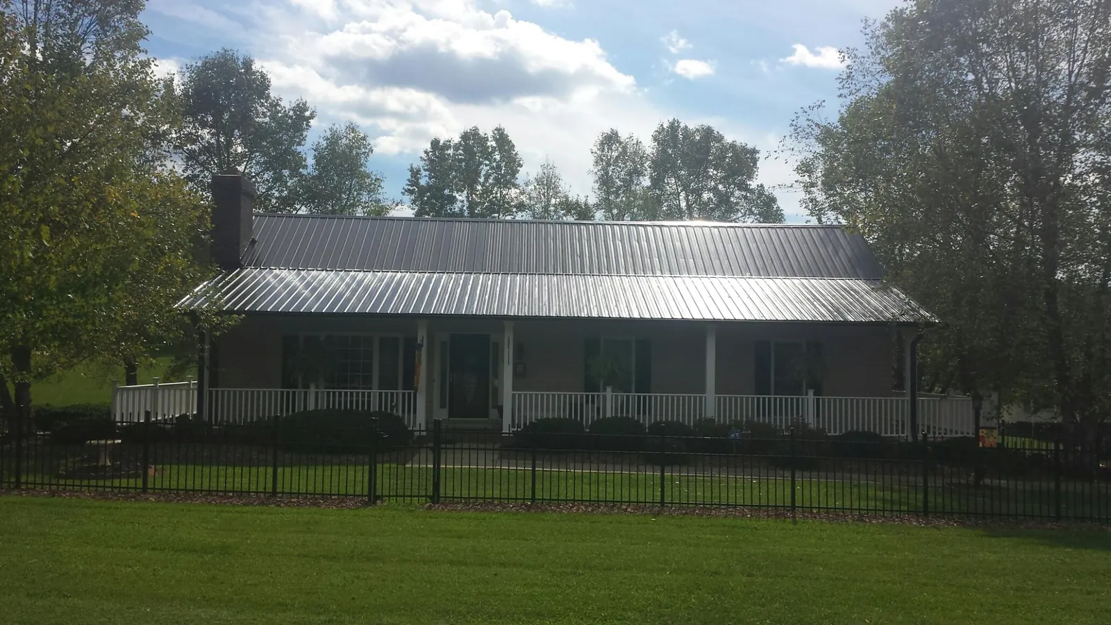 Gray metal roof on a brick ranch with a full width front porch — Gutter Guard Installation work by our crew in San Dimas