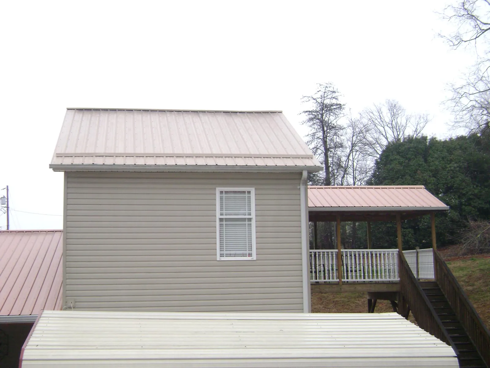 Tan metal roofs on a two story addition and attached porch, from a Roof Replacement job in San Dimas