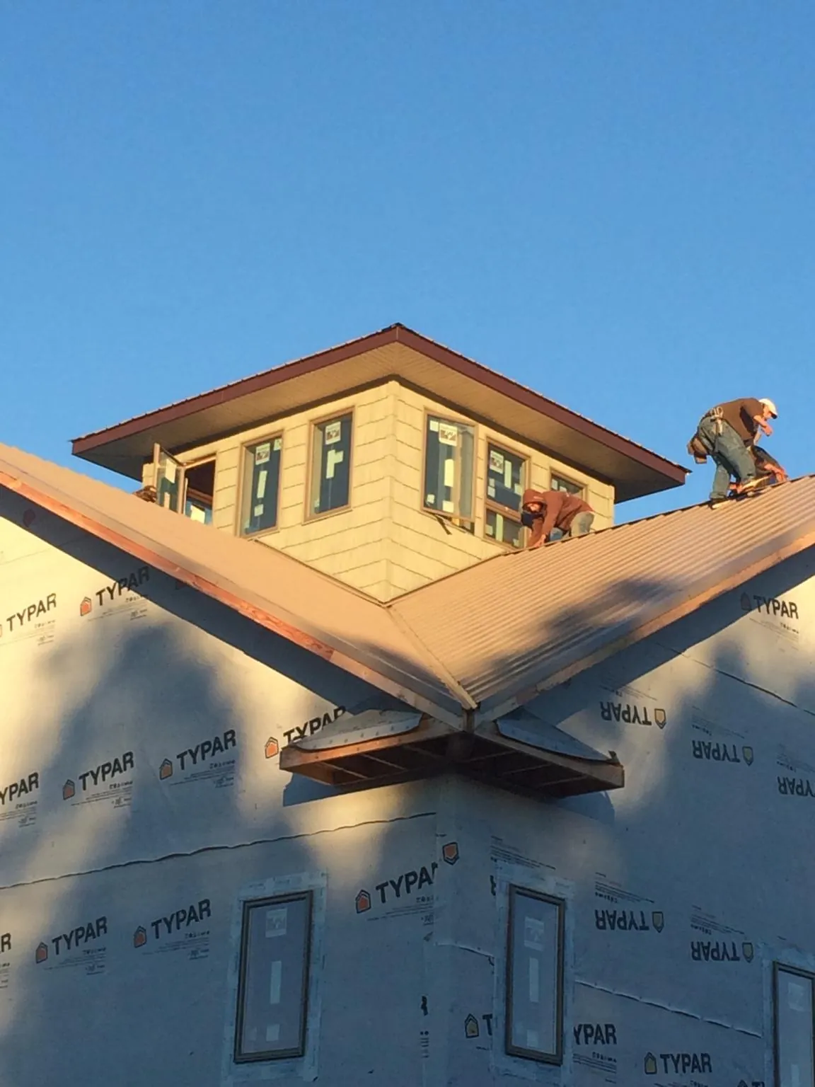 Roofers working around a rooftop cupola on a new metal roof at sunset — Roof Waterproofing in San Dimas by Roofing Brothers